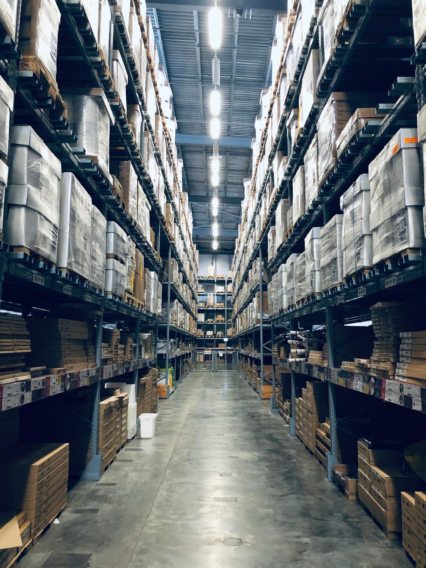 A tall warehouse aisle with stocked pallet racking on both sides