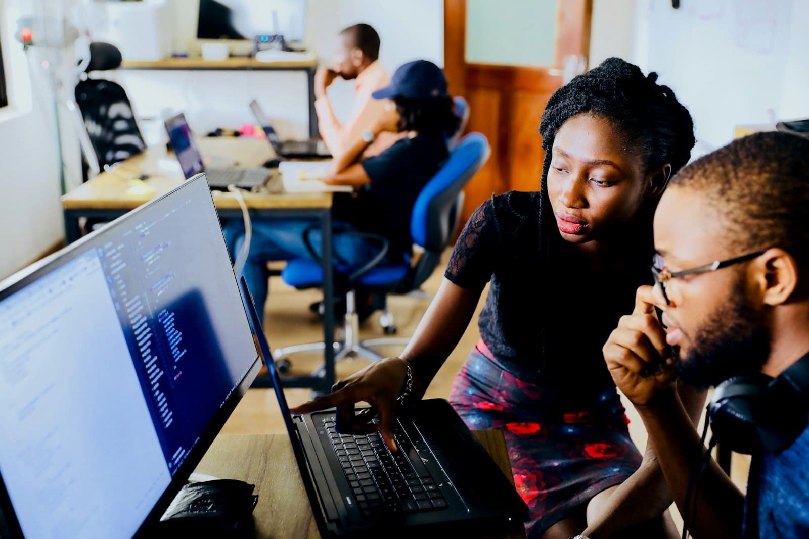 Two engineers reviewing code together on a large monitor